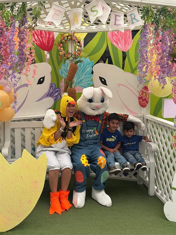 Adult in bunny costume with children on a decorated Easter bench in a colorful spring display