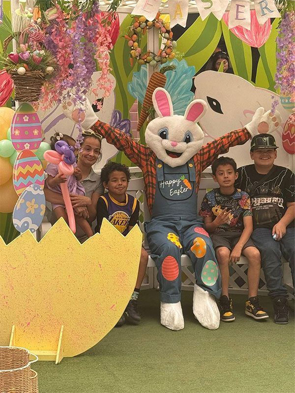 Children pose with the White Rabbit mascot in a colorful Easter-themed display.