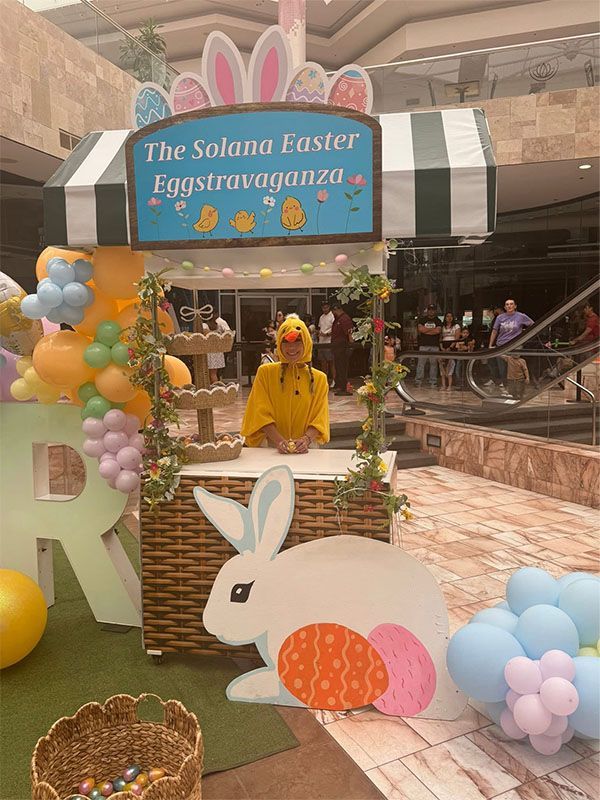 Easter display at a mall with a yellow bunny character, pastel decorations, and a sign reading “The Solana Easter Eggstravaganza”