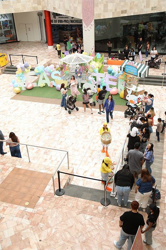People gathered around a colorful Easter display in a mall atrium.