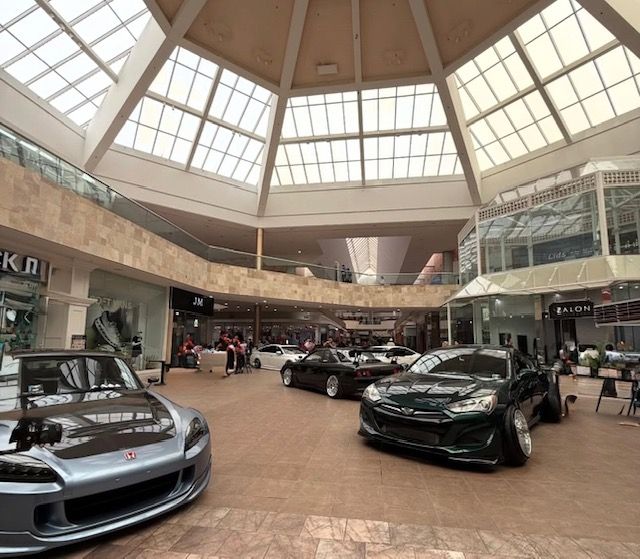 Indoor car showroom with several sports cars under a large skylight ceiling