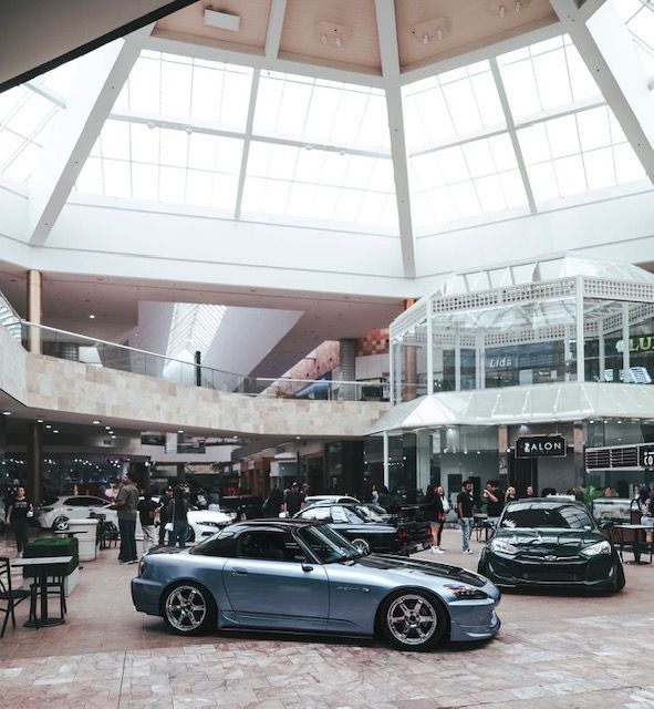 Luxury sports cars displayed in a bright indoor showroom with a glass-domed ceiling.