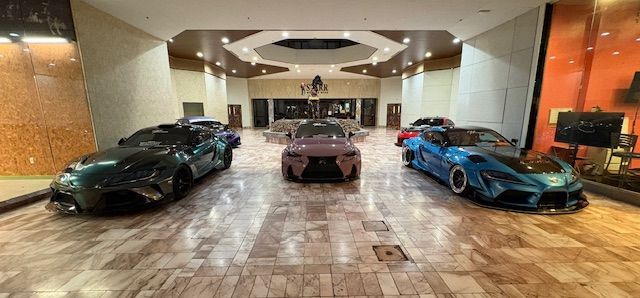Luxury car showroom with three sports cars on display under bright lights