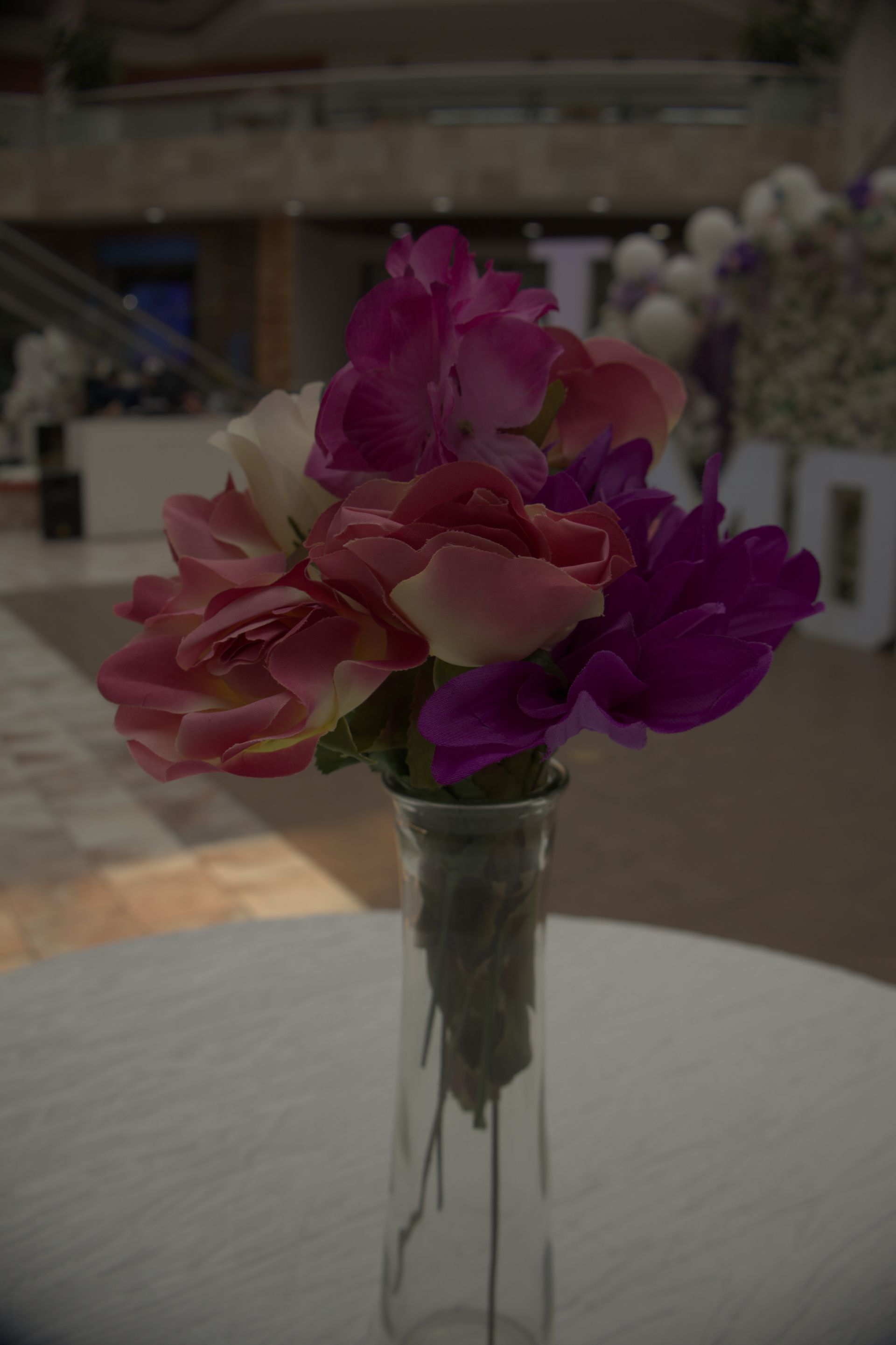 A small bouquet of pink and purple flowers in a clear glass vase on a table indoors.