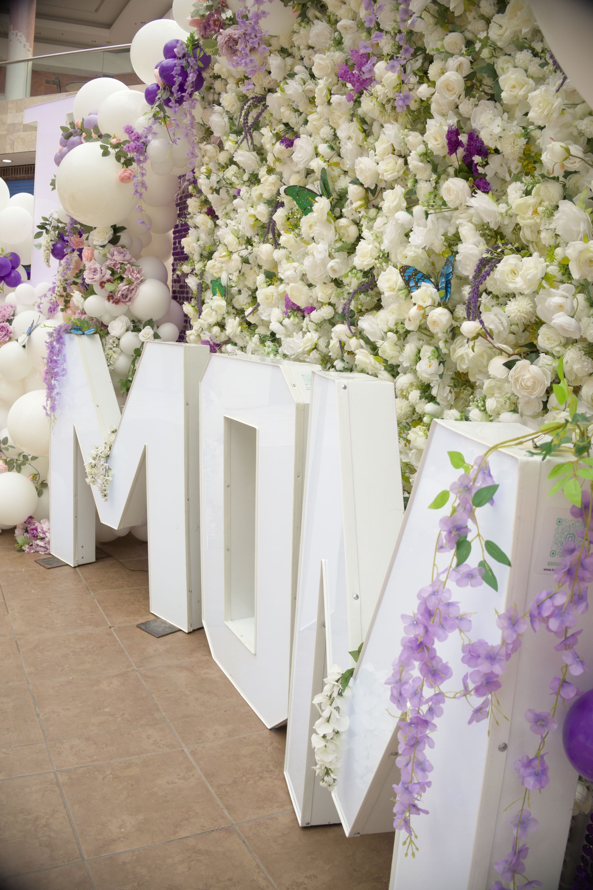 Large white floral letters with purple accents at an event backdrop