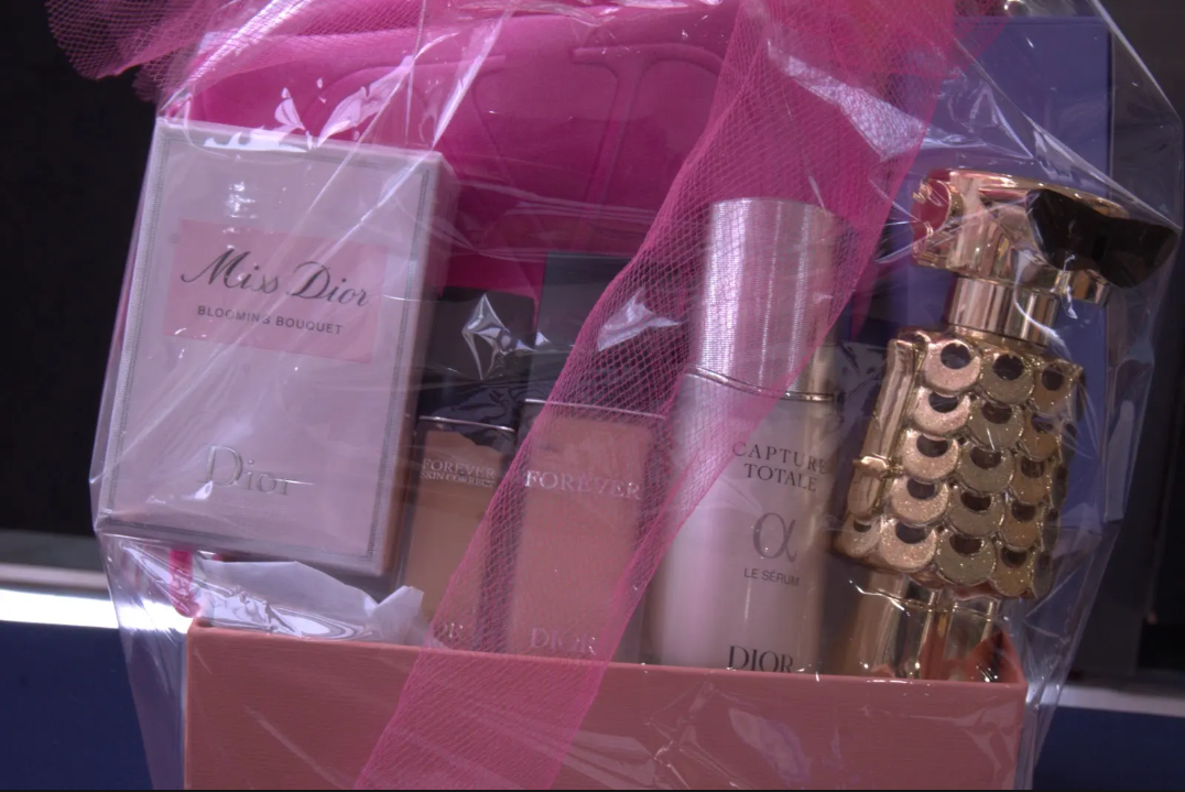 Gift set with pink ribbon, perfume bottle, lotion, and gold decorative container in a pink box