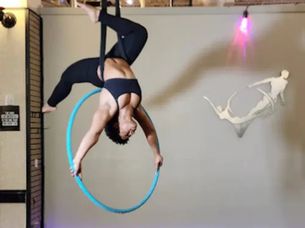 A woman is hanging upside down on an aerial hoop.