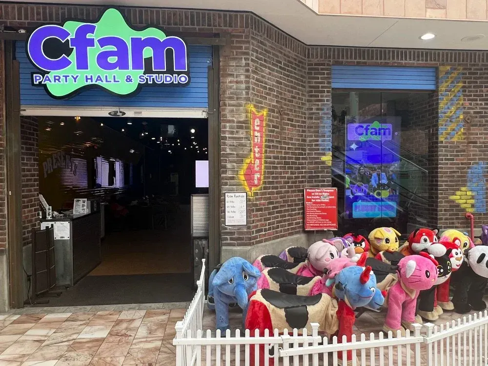 A group of stuffed animals are sitting outside of a cfam party hall and studio.