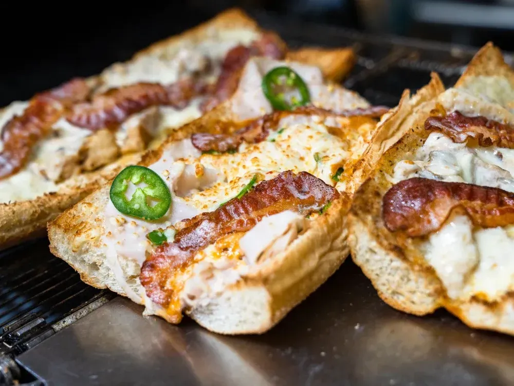 A close up of three sandwiches on a grill.