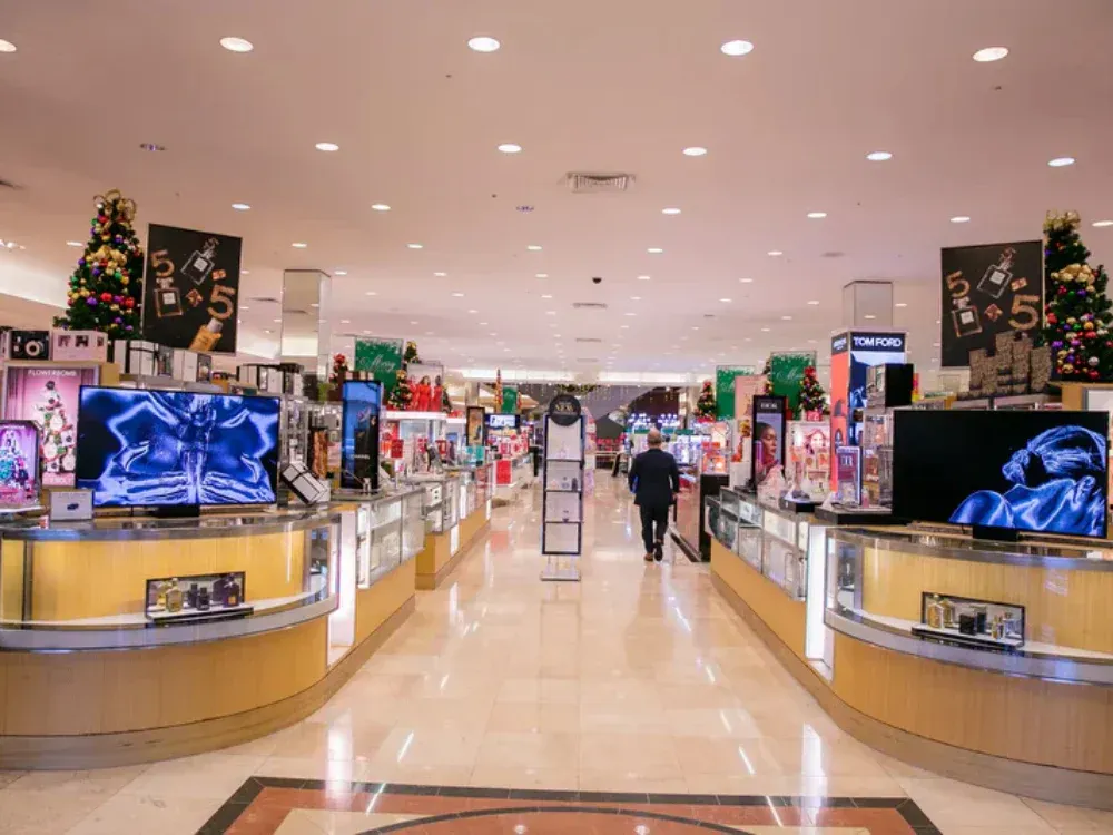 A man is walking through a store filled with lots of televisions.