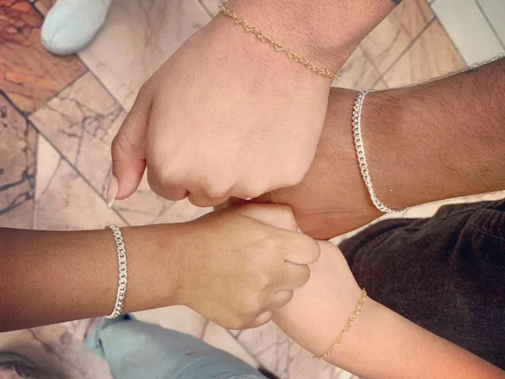 A group of people wearing bracelets are putting their hands together