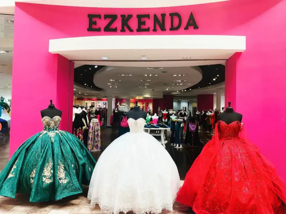 Two dresses are on display in front of a store called ezkenda