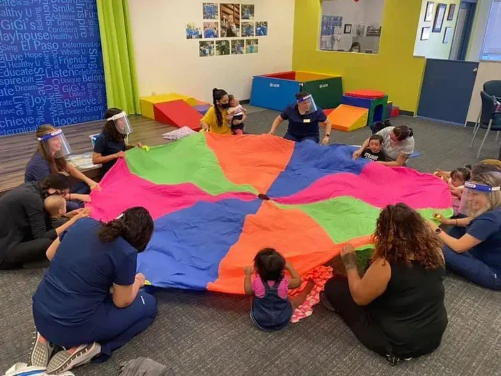 Children seated in a circle holding a colorful parachute in a classroom activity
