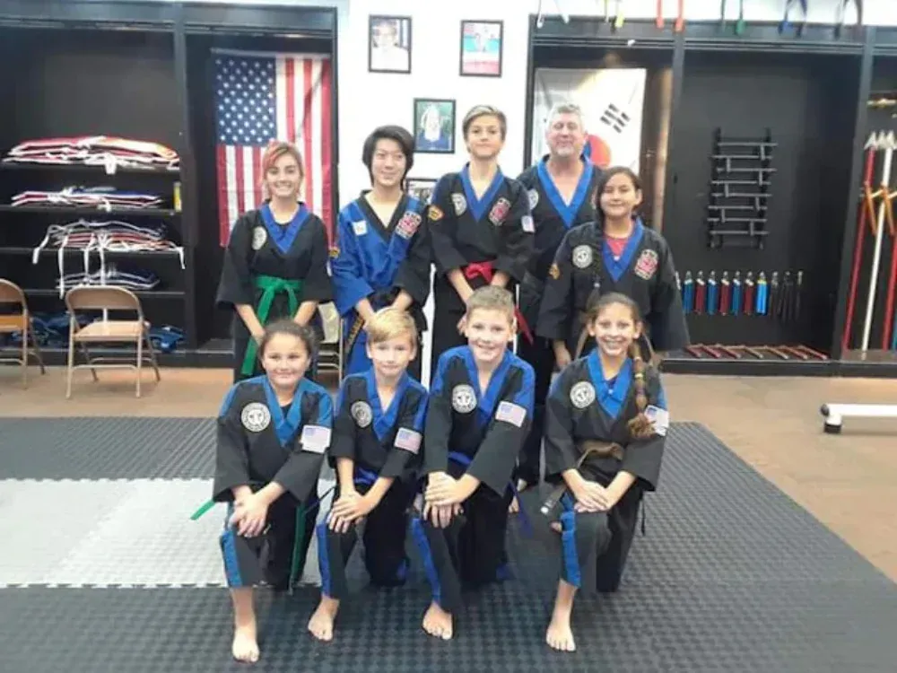 A group of kids in martial arts uniforms pose for a picture