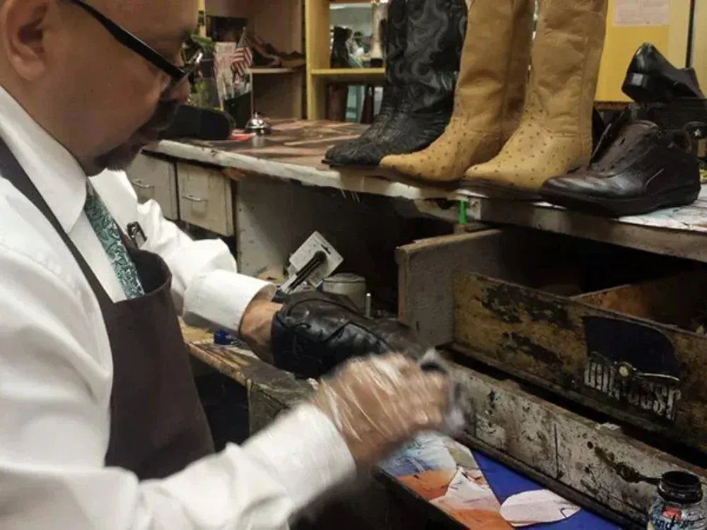 A man is working on a pair of cowboy boots