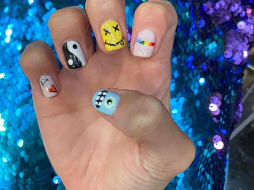 A close up of a person 's nails with different designs on them.