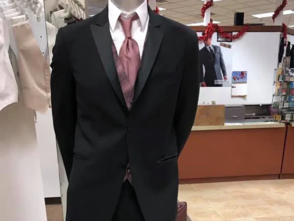 A mannequin wearing a black tuxedo and pink tie