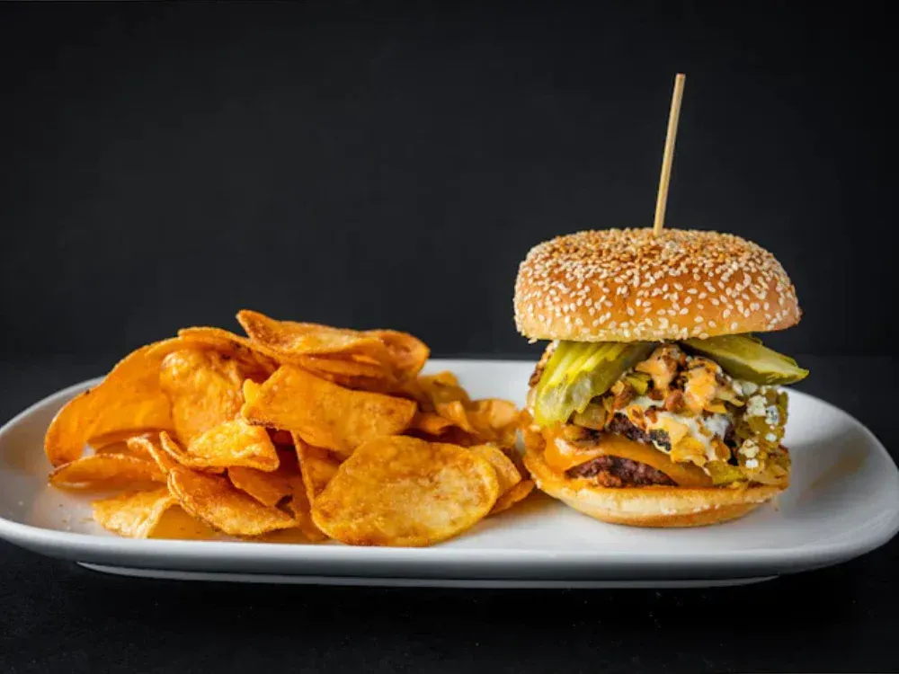 A white plate topped with a hamburger and potato chips.