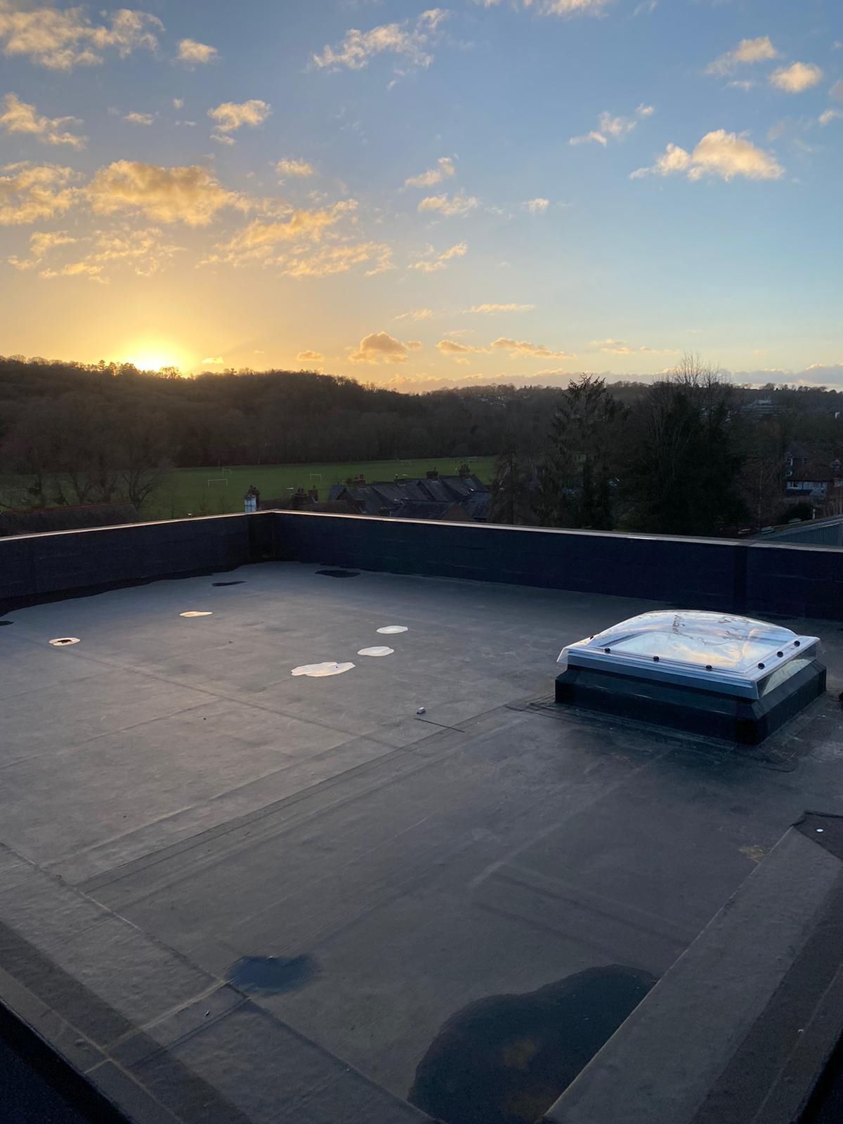 a roof with a skylight and a sunset in the background