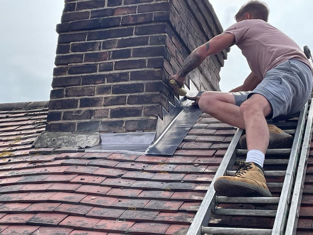 a man on a ladder working on a brick chimney