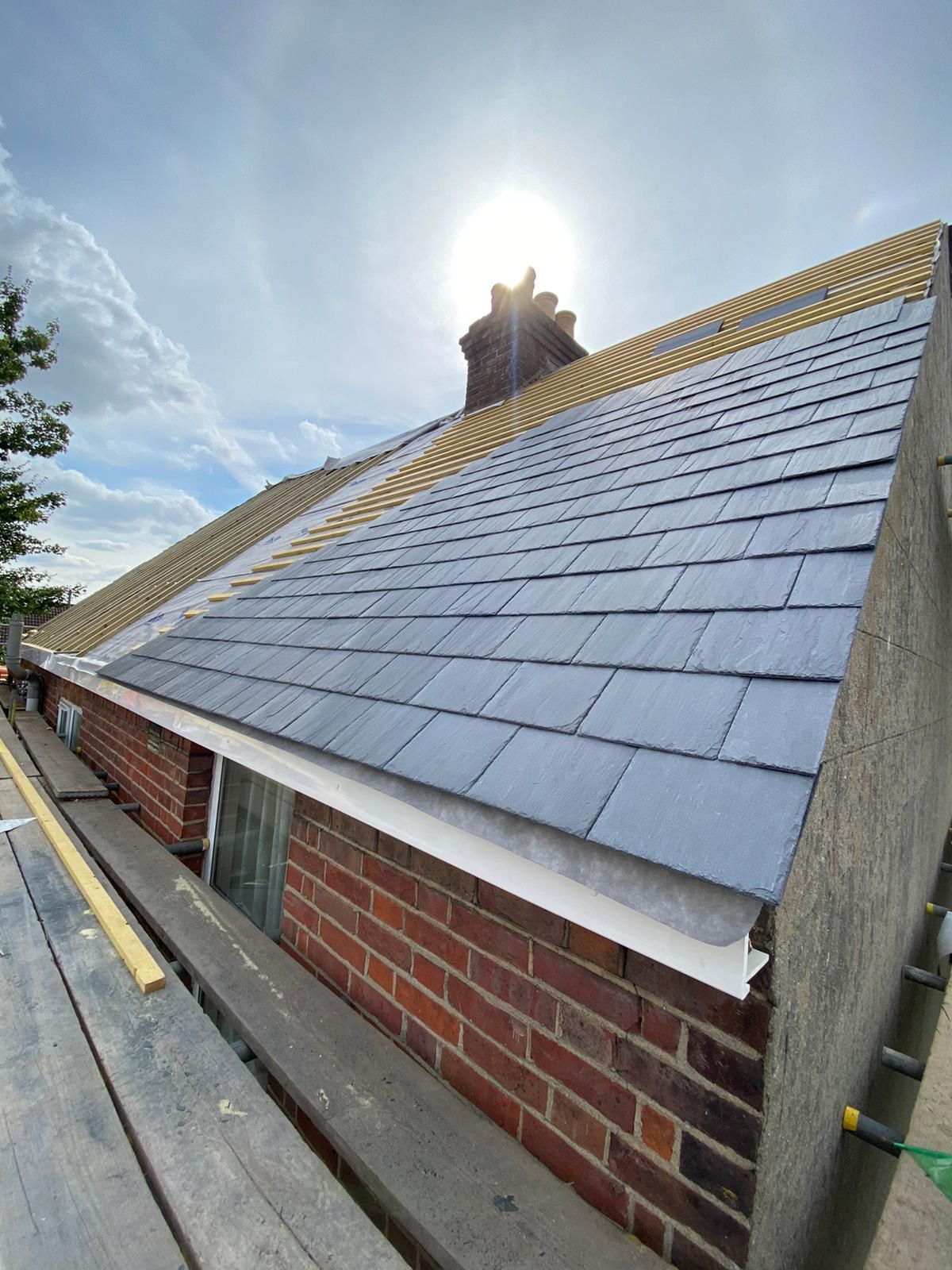 A slate roof is being installed on a brick building.