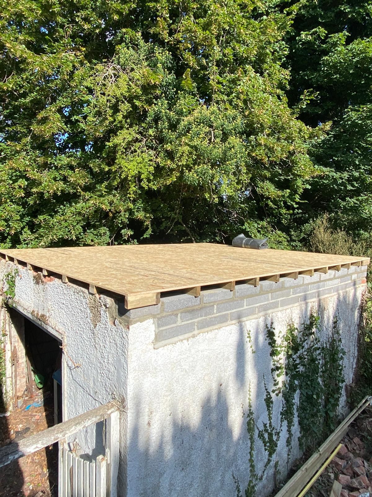 a white building with a wooden roof and trees in the background