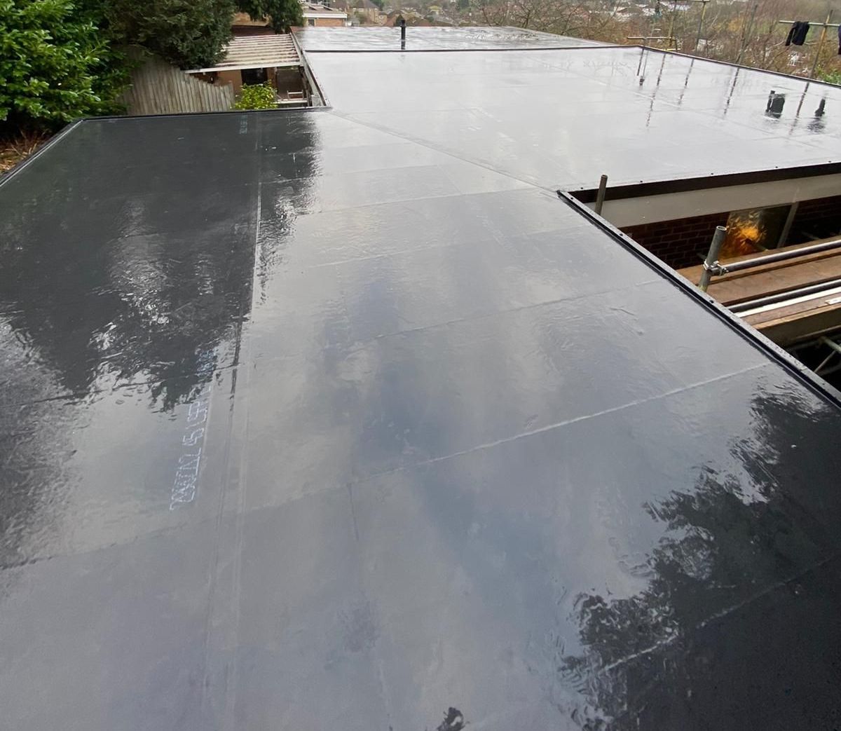 A black roof with a reflection of trees in it.