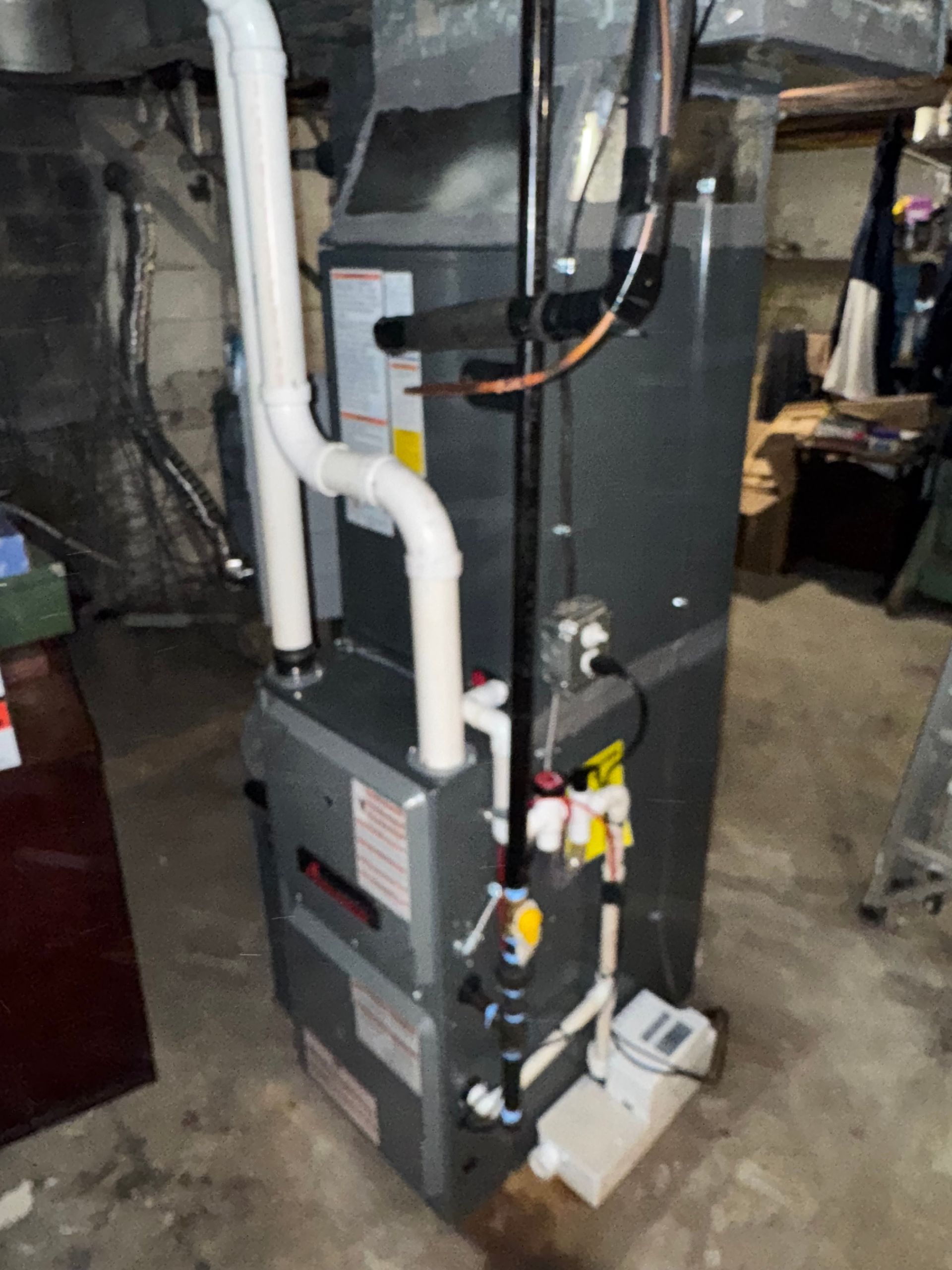 Furnace unit in a basement, with connected pipes and electrical components.