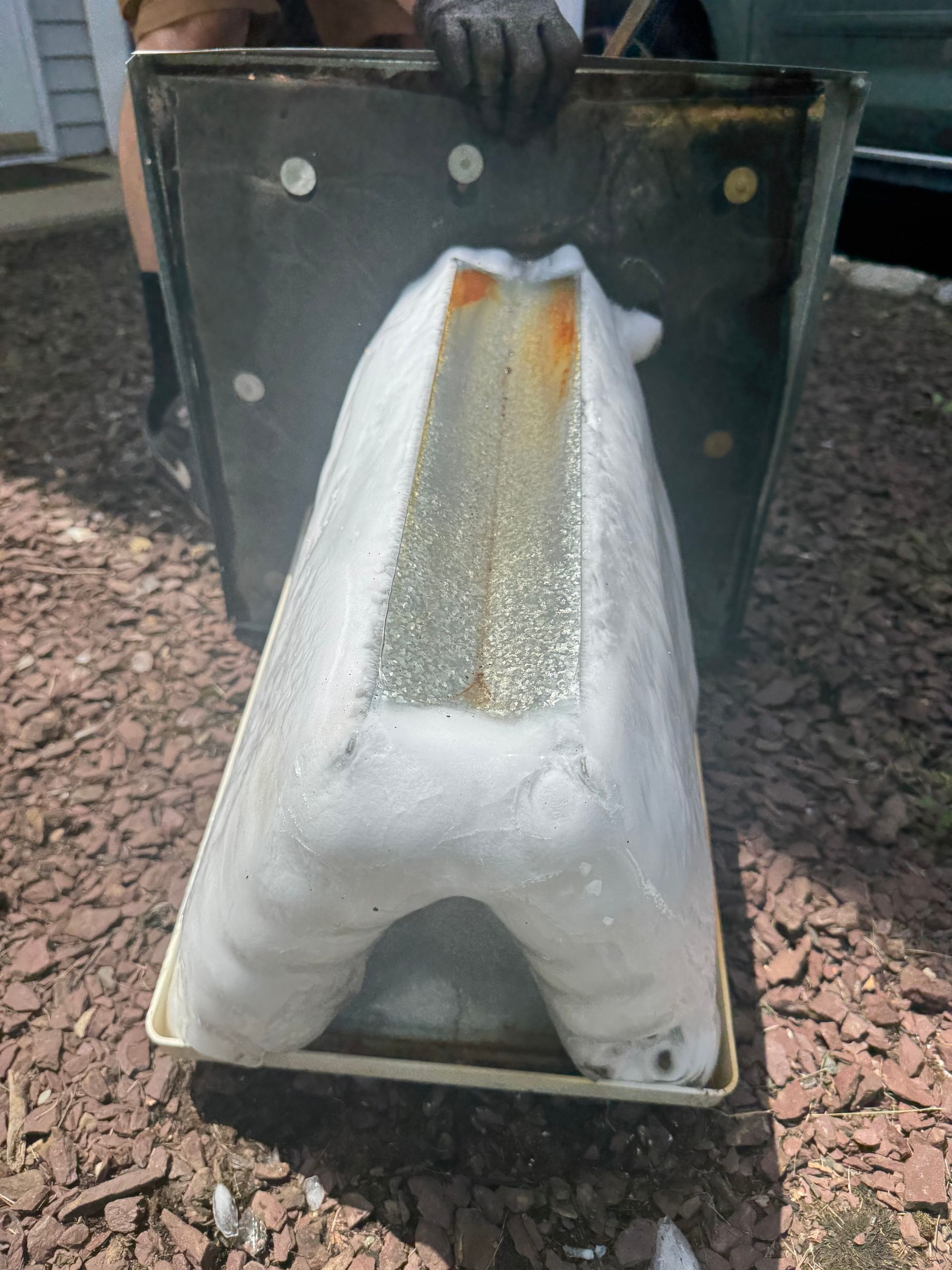 A foam-filled container shaped like a capital letter A is held by gloved hands outside.