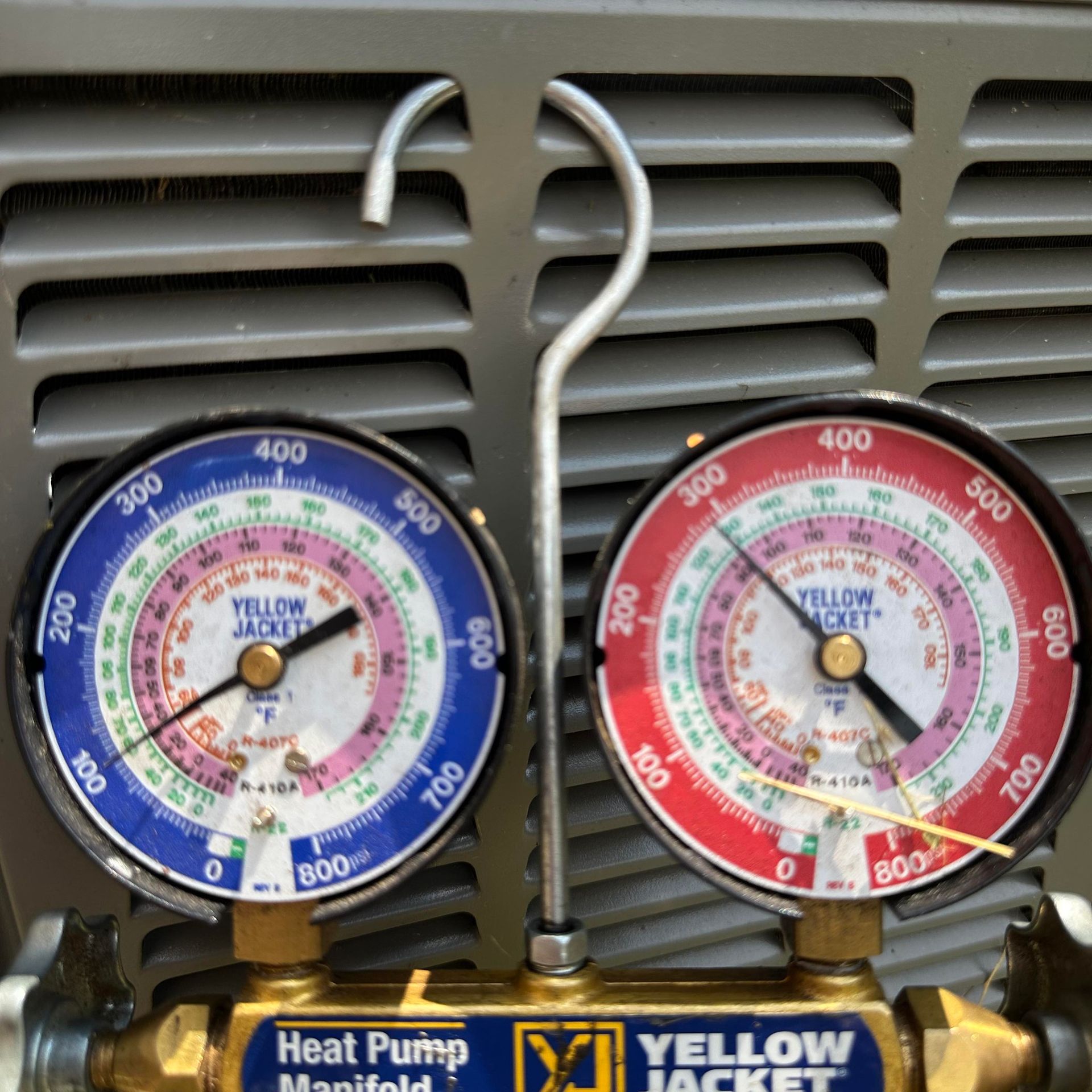 Two pressure gauges attached to an HVAC unit, displaying pressure readings.