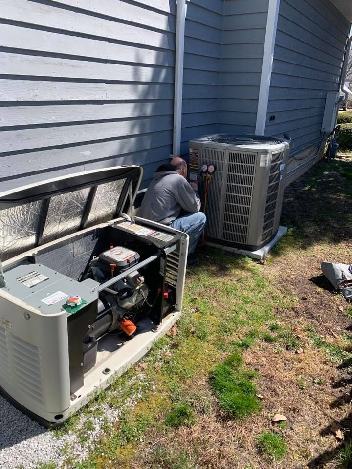 A person working on an outdoor generator next to a house and air conditioning unit.