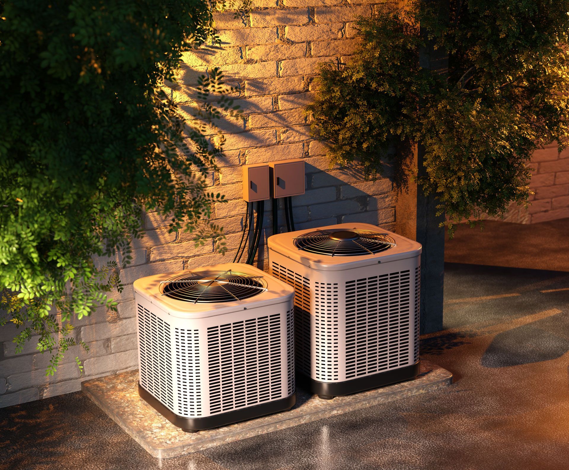 Two outdoor air conditioners beside a brick wall, lit by warm sunlight and partly shaded by trees
