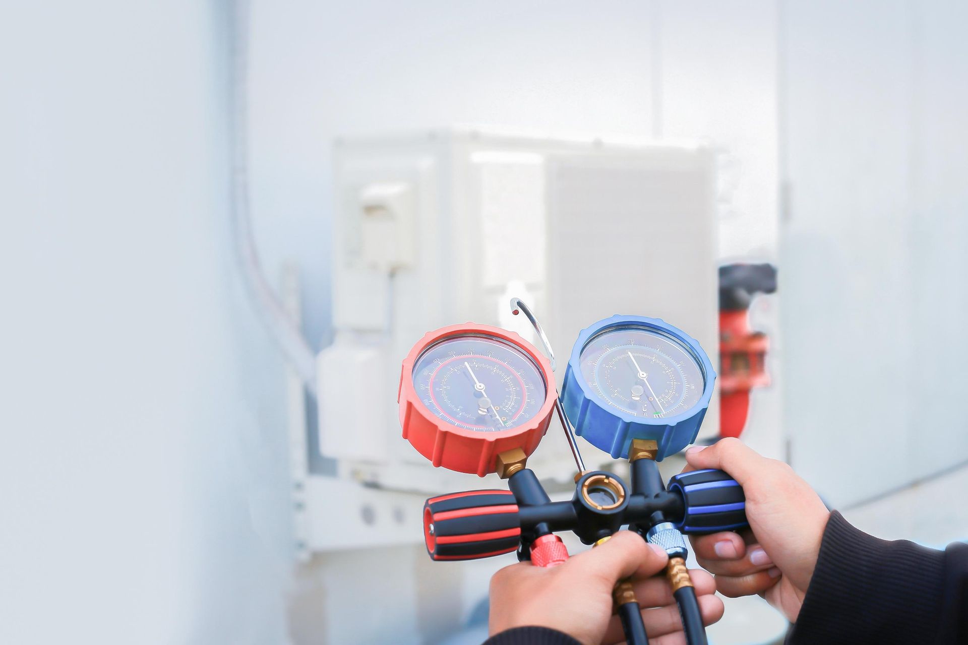 A person is holding a pair of pressure gauges in their hands.