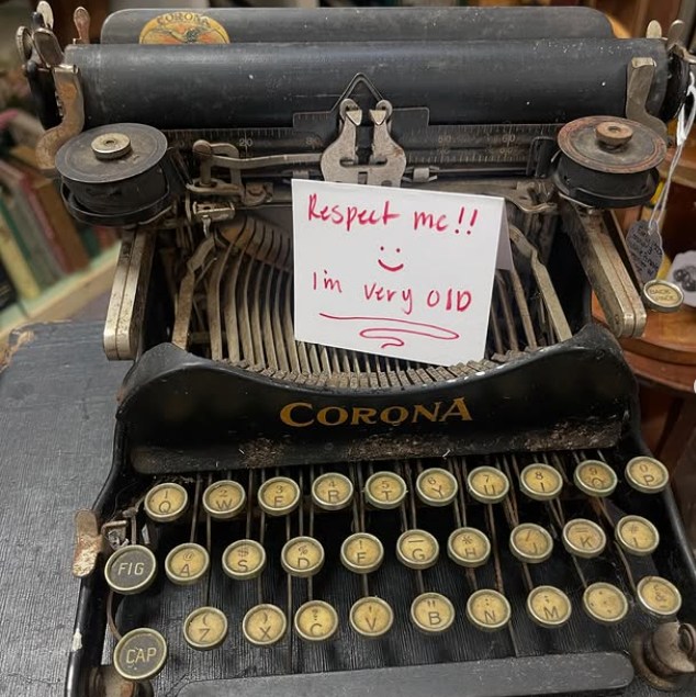Antique black Corona typewriter with a note reading