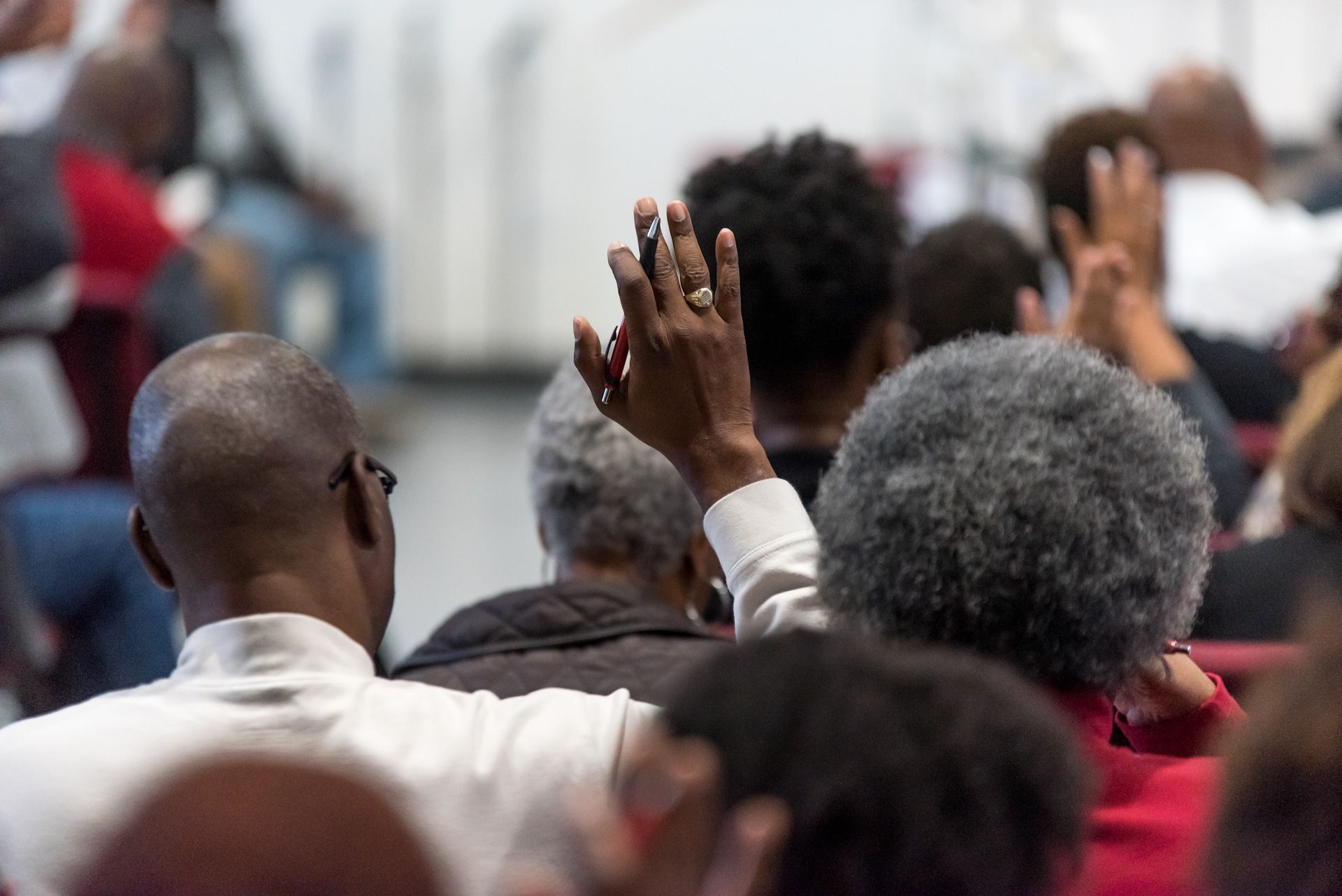 A group of people are sitting in a room with their hands up.