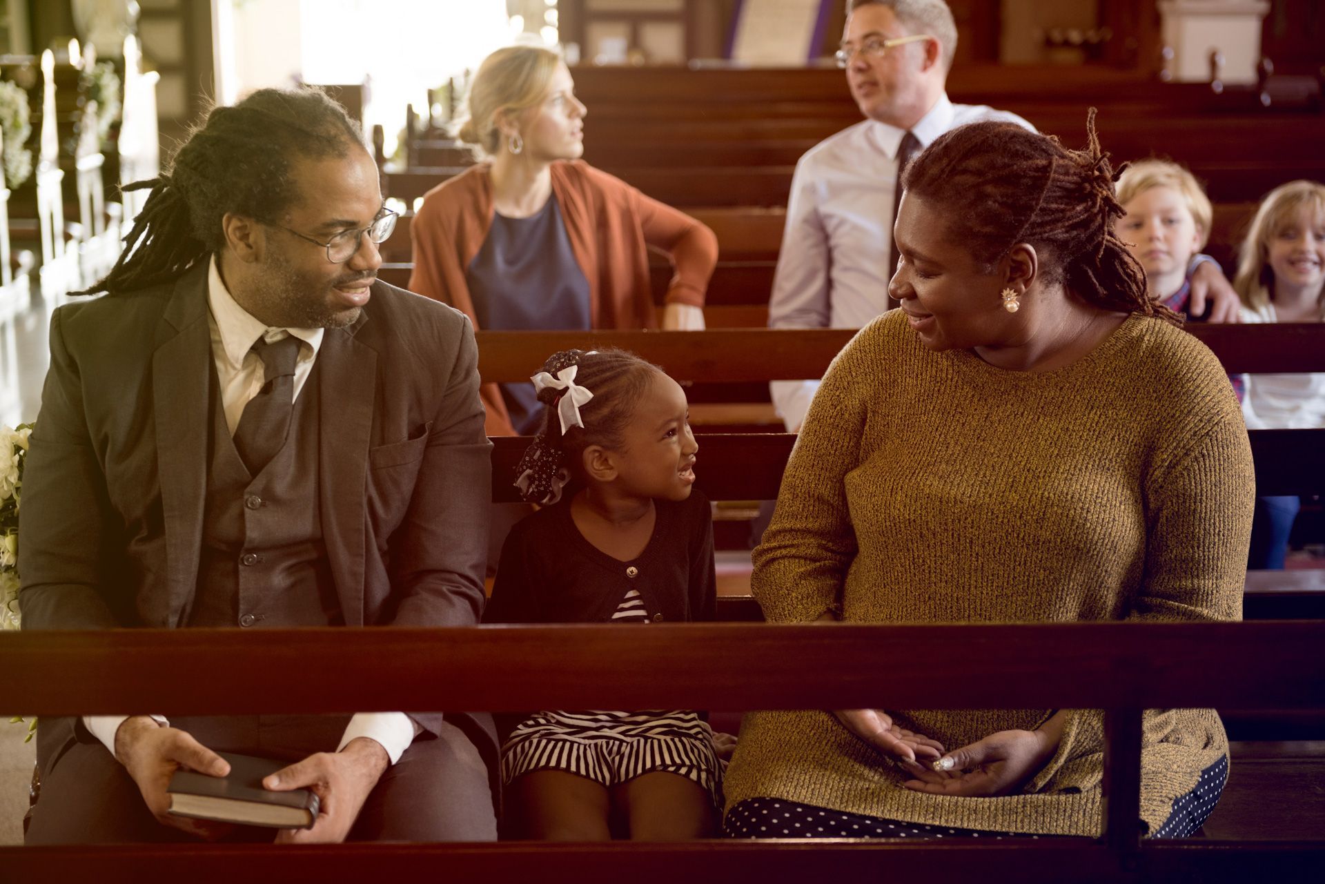 A group of people are sitting in a church talking to each other.