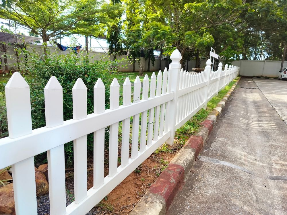 A white picket fence is along the side of a road.
