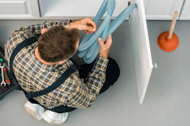 Installateur benutzt mechanische Reinigungsgeräte bei verstopften Rohr- und Kanalsystemen.