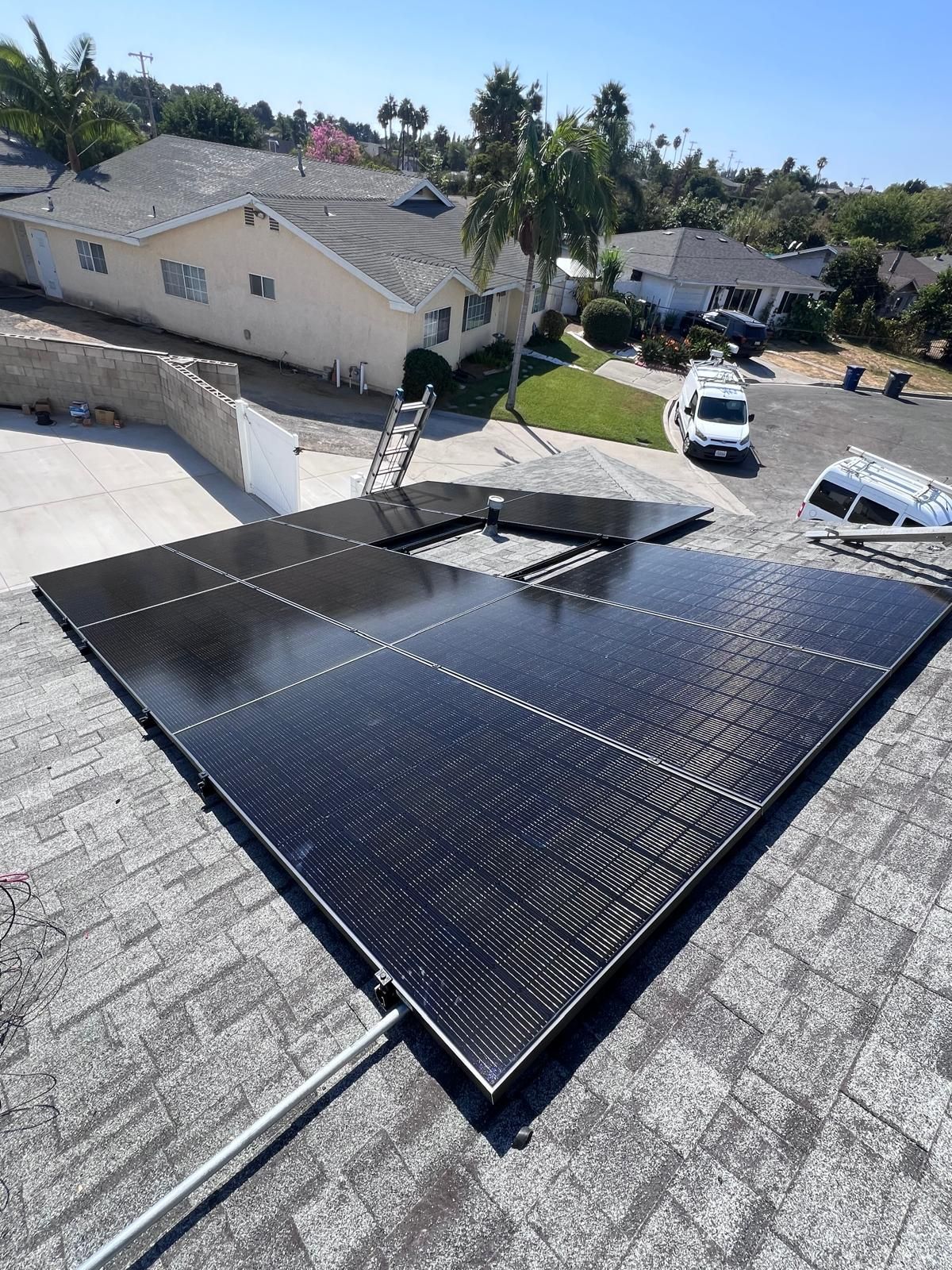 Solar panels mounted on a sloped roof in a suburban neighborhood under bright sunlight