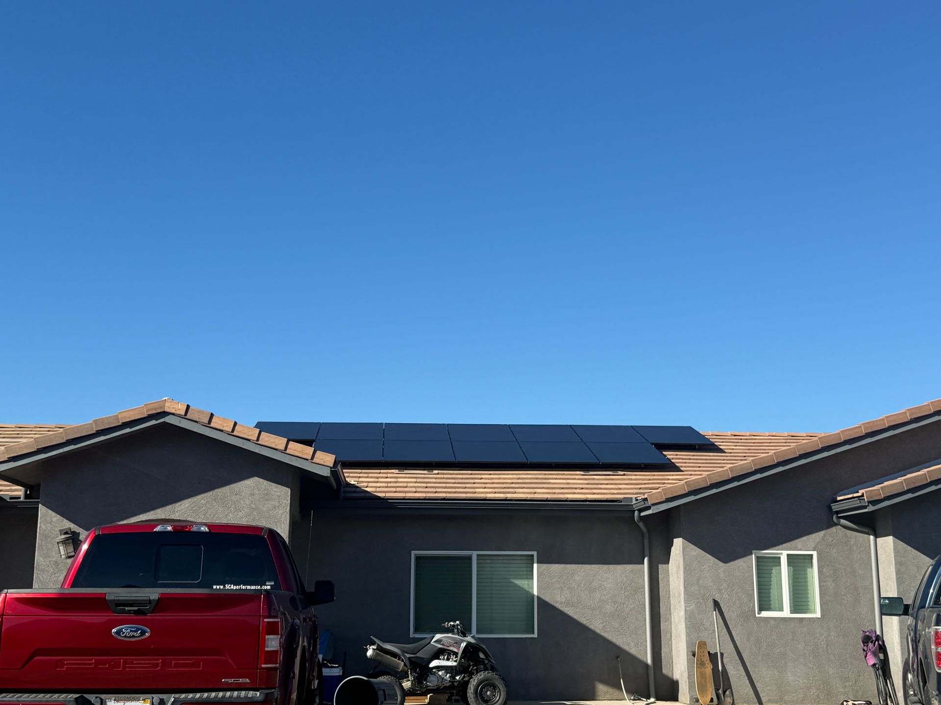 Suburban house with solar panels on the roof and a red pickup truck in the driveway