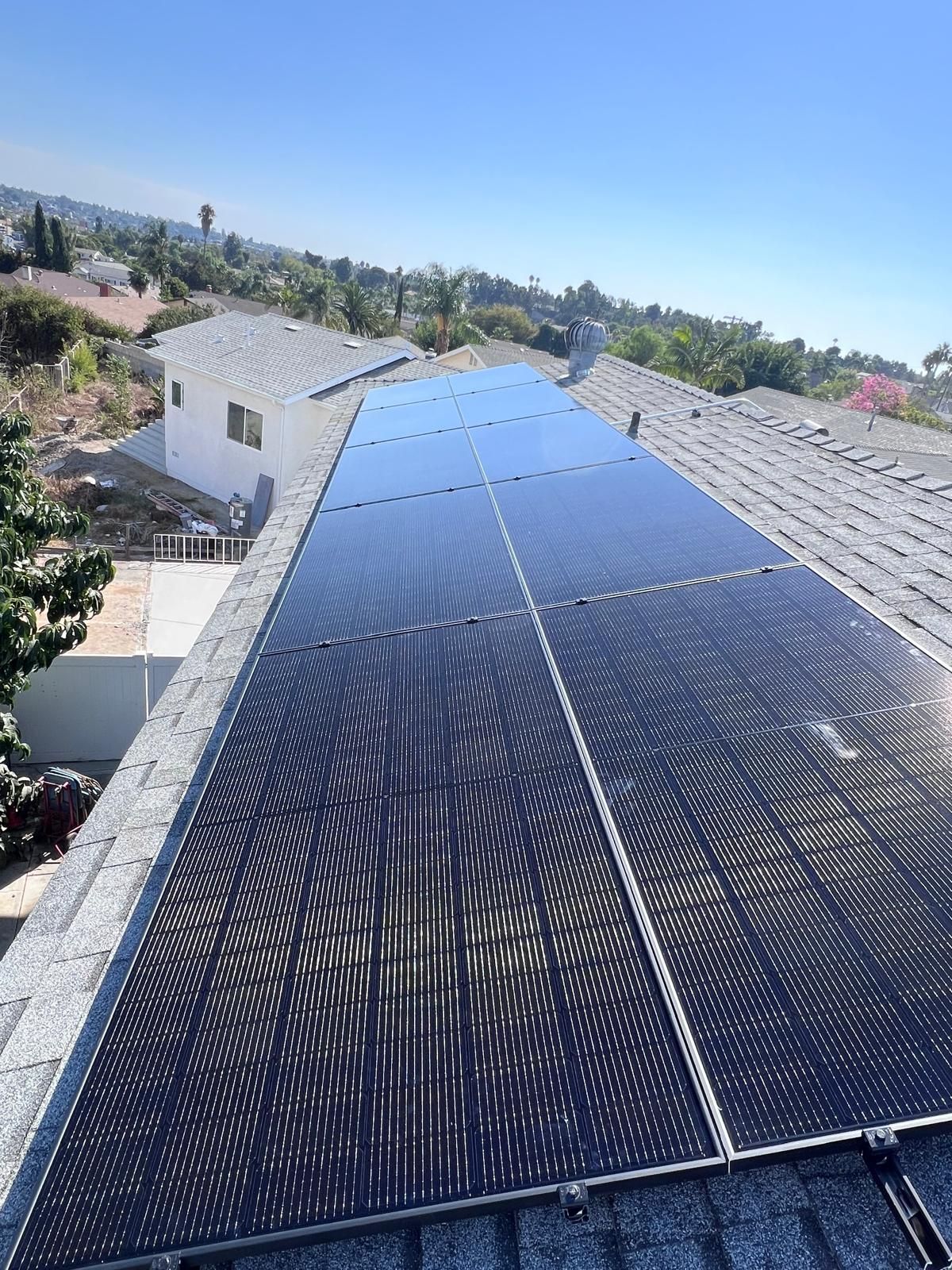 Solar panels covering a residential roof under a clear blue sky