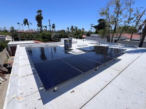 Rooftop solar panels installed on a flat white roof under a clear blue sky
