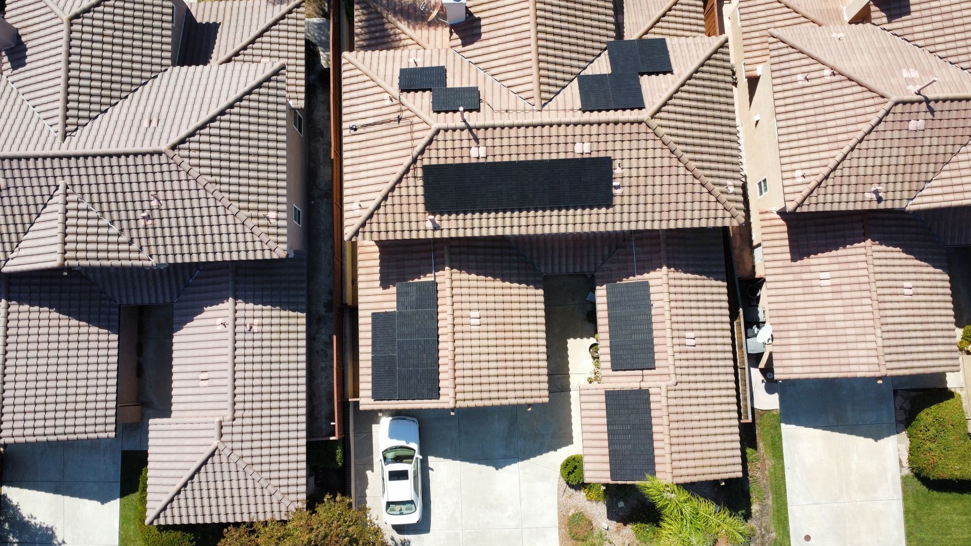 Aerial view of tiled rooftops, driveways, and parked cars in a suburban neighborhood