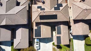Aerial view of several tiled residential rooftops with skylights and patches of sunlight.