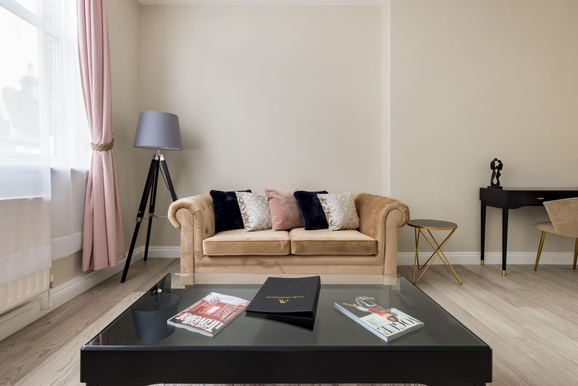 Modern living room with beige sofa, black coffee table, floor lamp, and pink curtains by a large window
