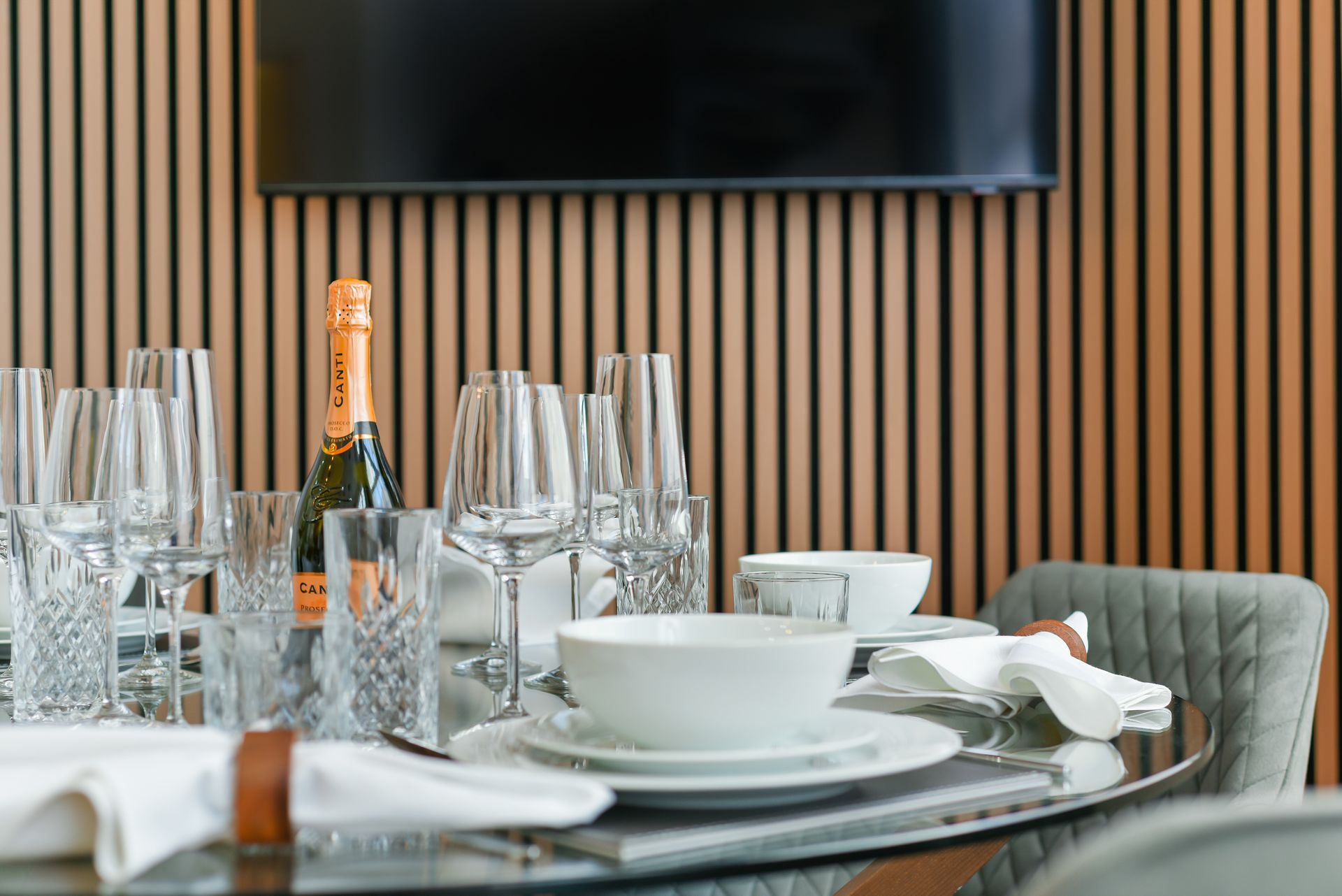 Set dining table with champagne, glasses, white dishes, and napkins in a modern room