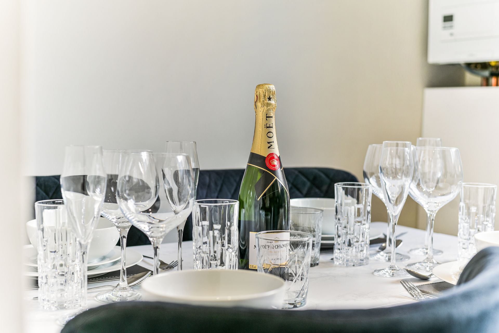 Set dining table with champagne bottle, wine glasses, and plates in a bright room