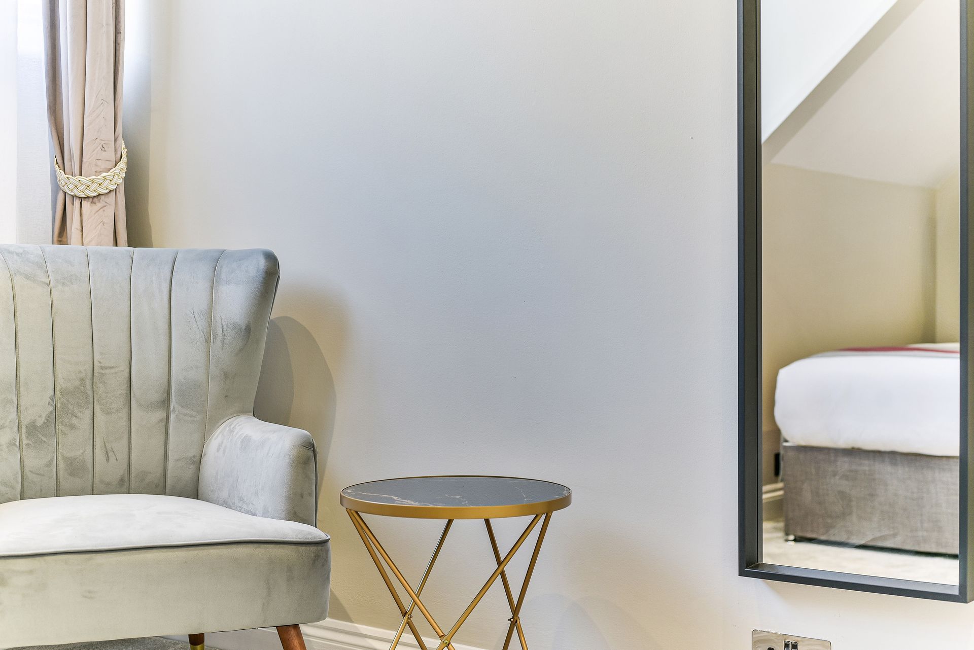 Living room corner with a gray armchair, small round table, and wall mirror