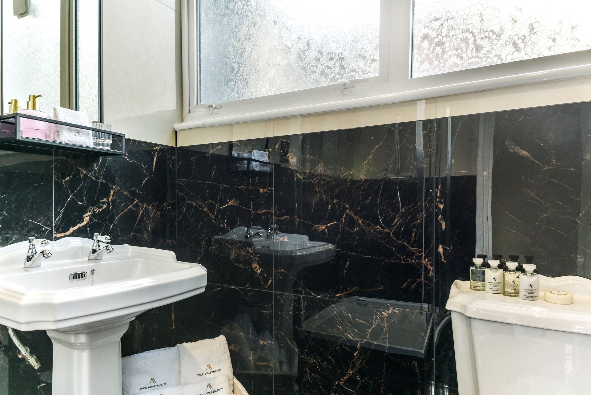 Small black-and-white bathroom with sink, toilet, bathtub, and frosted window.