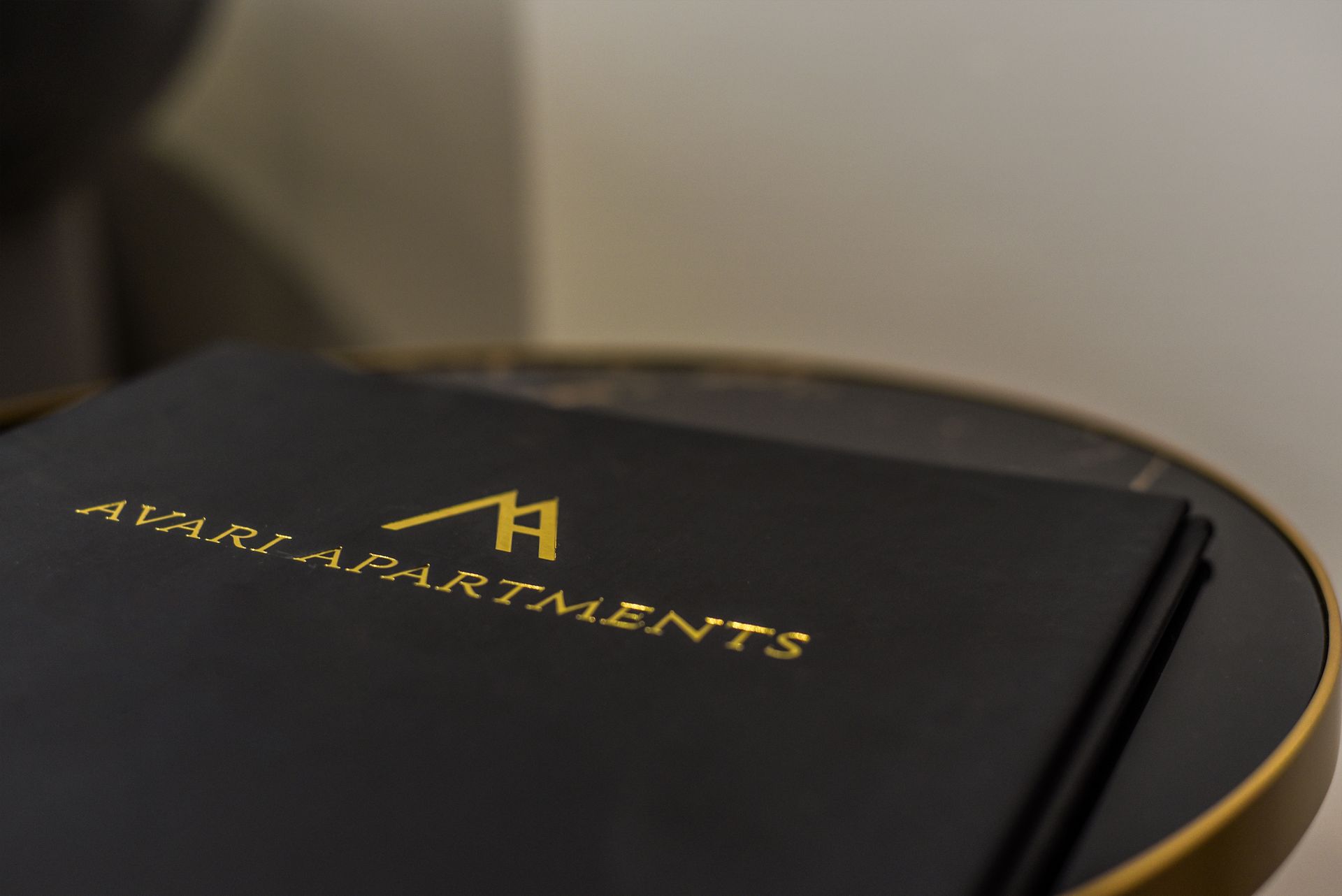 Black Ari Apartments folder on a round gold-trimmed table in a softly lit room